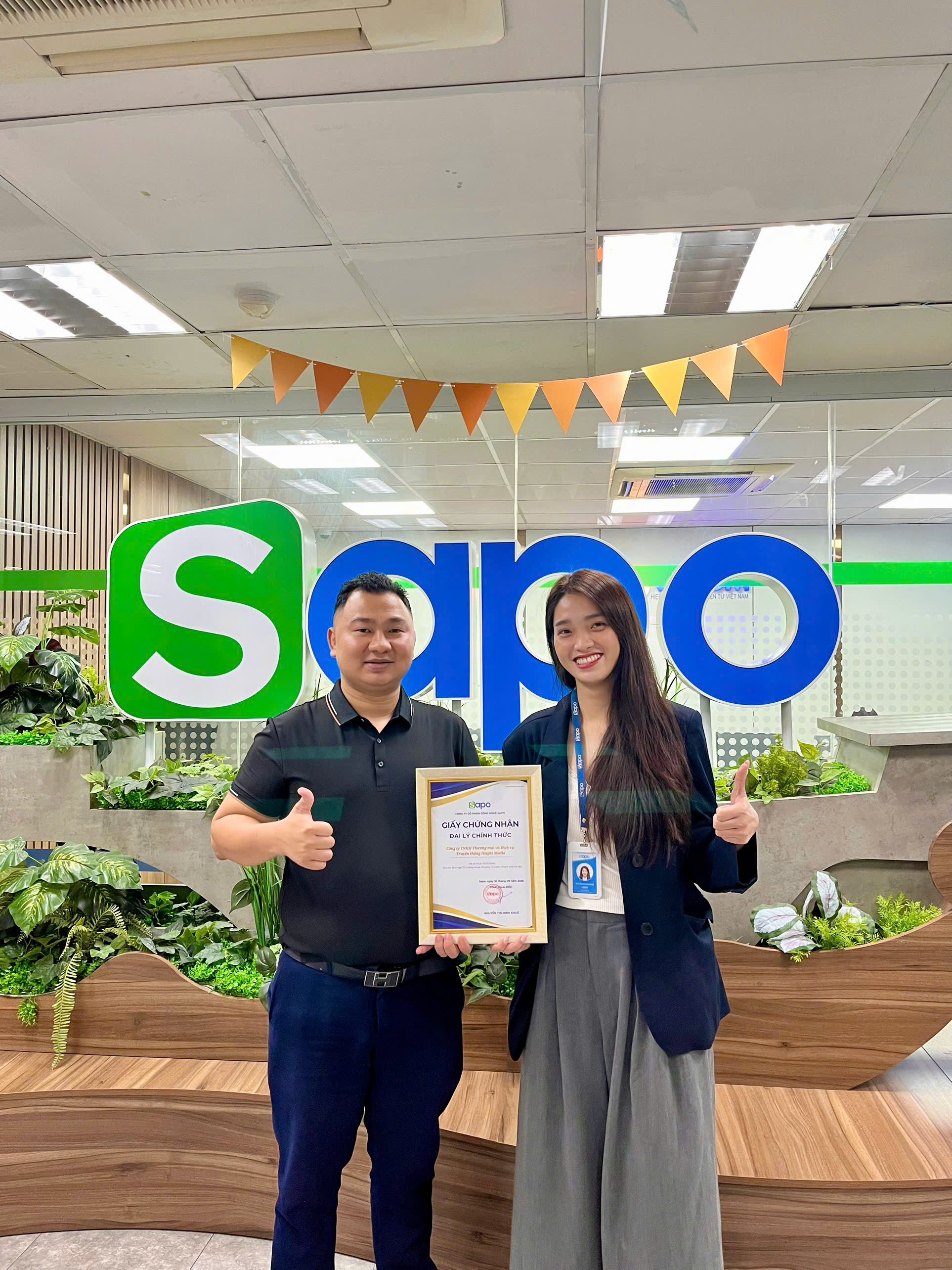 CEO Height Media Bảo Phúc chụp ảnh lưu niệm cùng đại diện Sapo trước logo Sapo